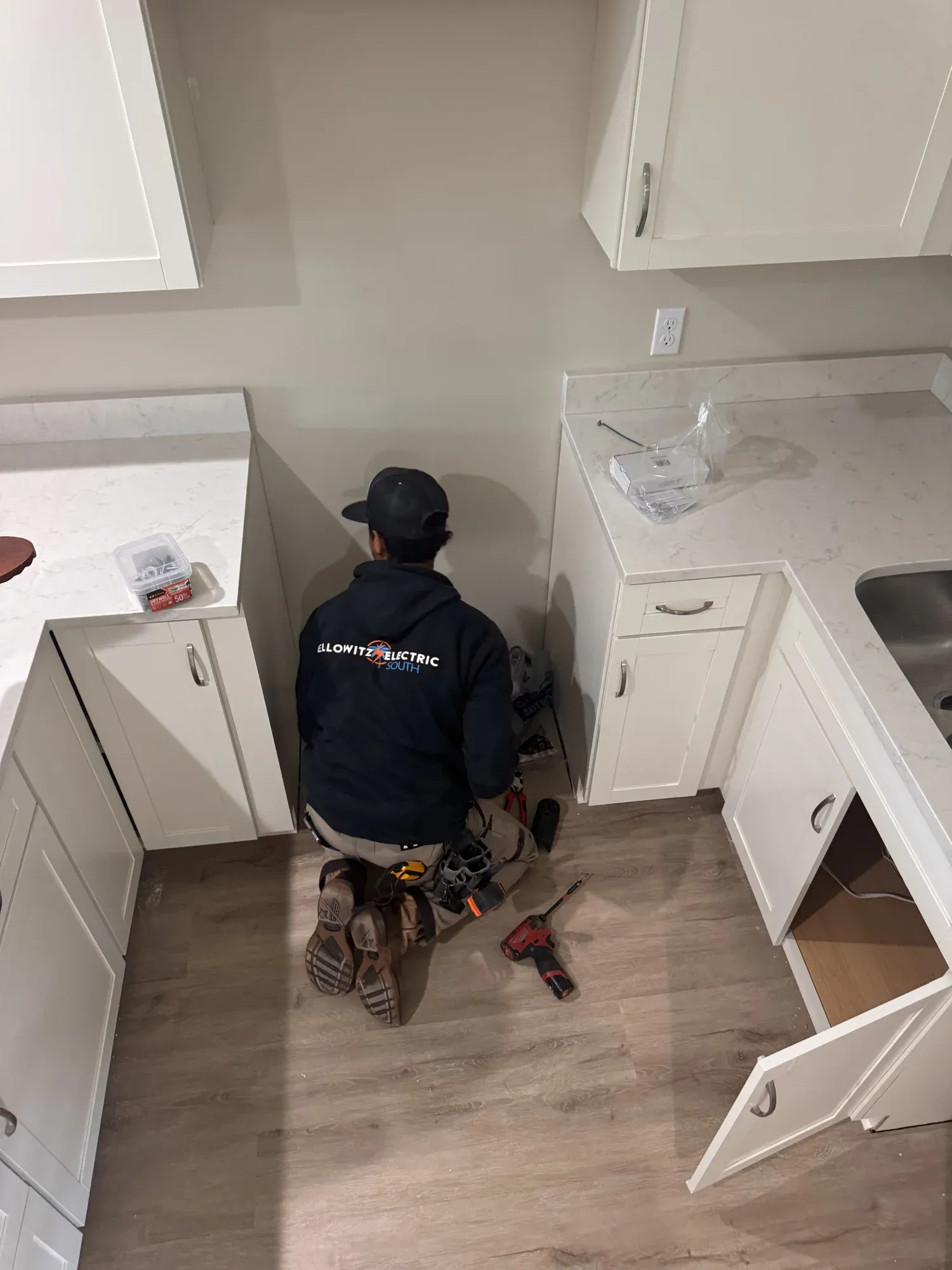 Ellowitz electrician kneeling at the kitchen cabinets of a new home