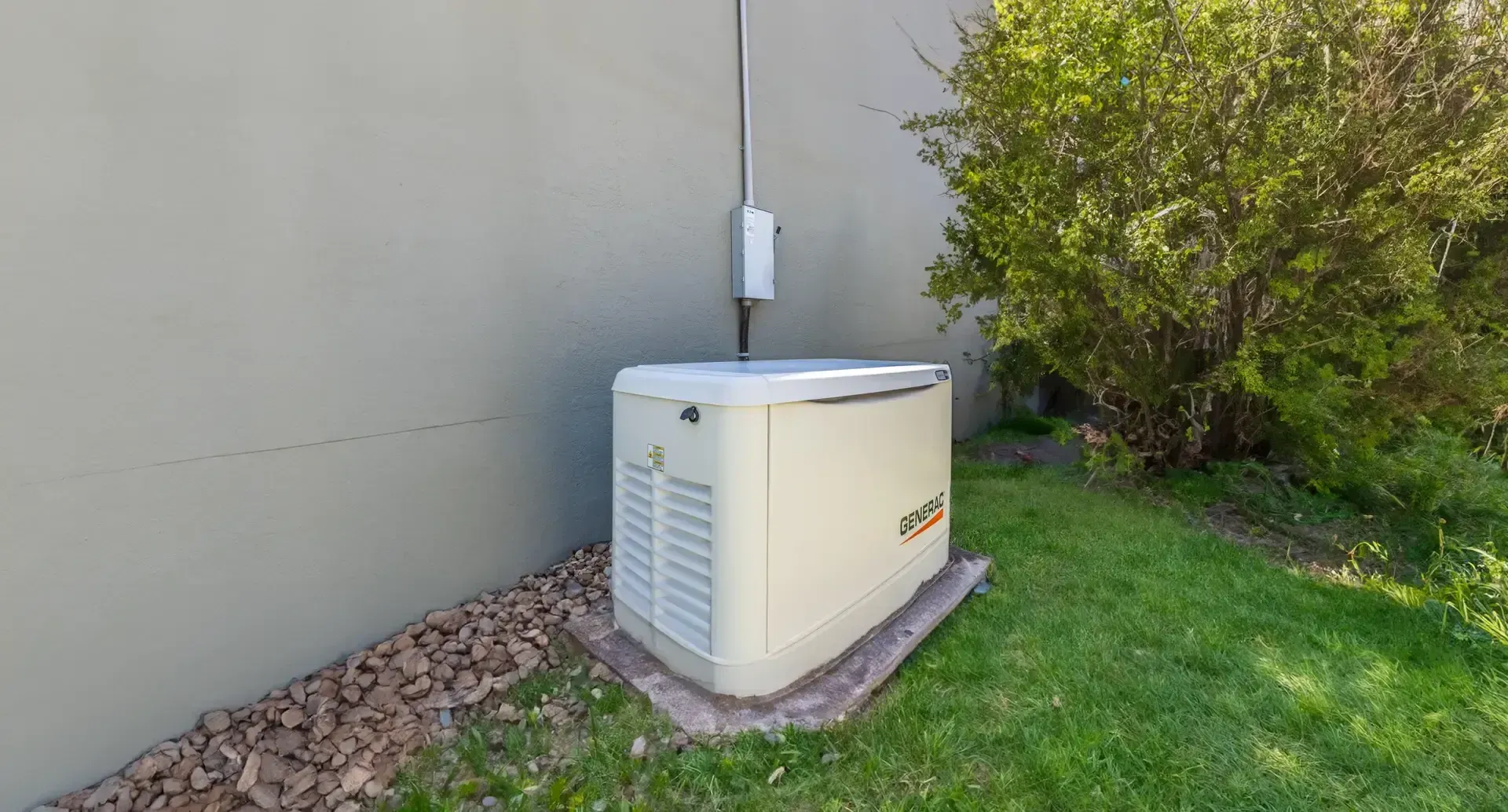 Generac standby generator on a gravel bed next to the house
