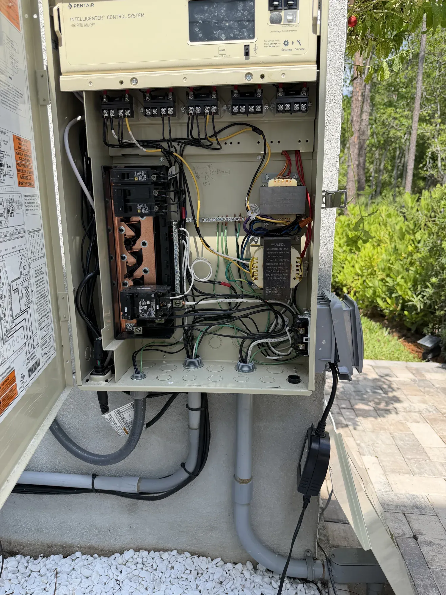 Outdoor equipment panel with breakers and controls installed beside a paver patio